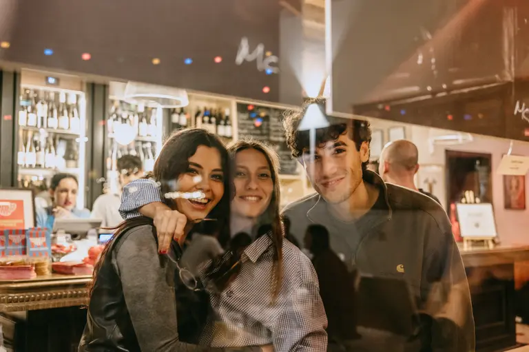 Tre amici sorridono dietro la vetrina della Cantina